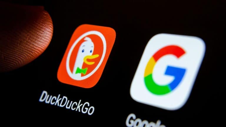 A close-up of a smartphone screen shows the DuckDuckGo iPhone app icon, featuring a duck, next to the Google app icon with its colorful "G" logo. A finger is partially visible near the DuckDuckGo icon.