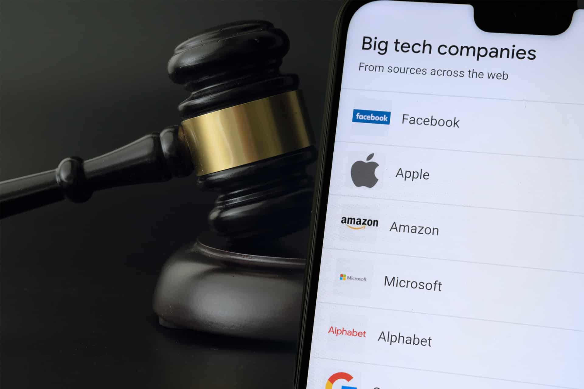 A judge’s gavel lies next to a smartphone screen displaying a list of big tech companies, including Facebook, Apple, Amazon, Microsoft, and Alphabet, hinting at legal issues tied to the DMA’s impact on tech firms and their AI assistants.