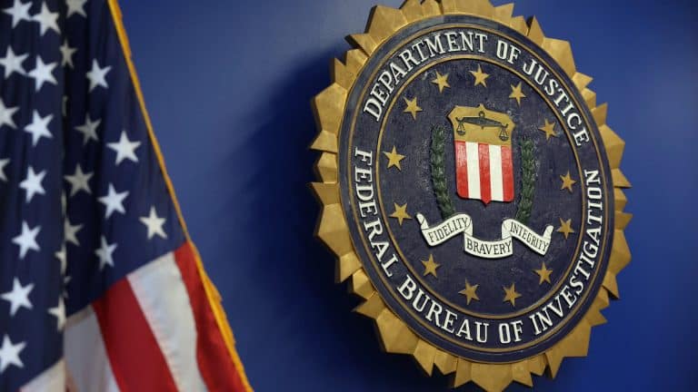 A large FBI seal is mounted on a blue wall next to a partially visible American flag, echoing the values of "Fidelity, Bravery, Integrity"—much like the rigorous standards set by each iOS security update, including iOS 15.8.8 and iOS 16.7.16.