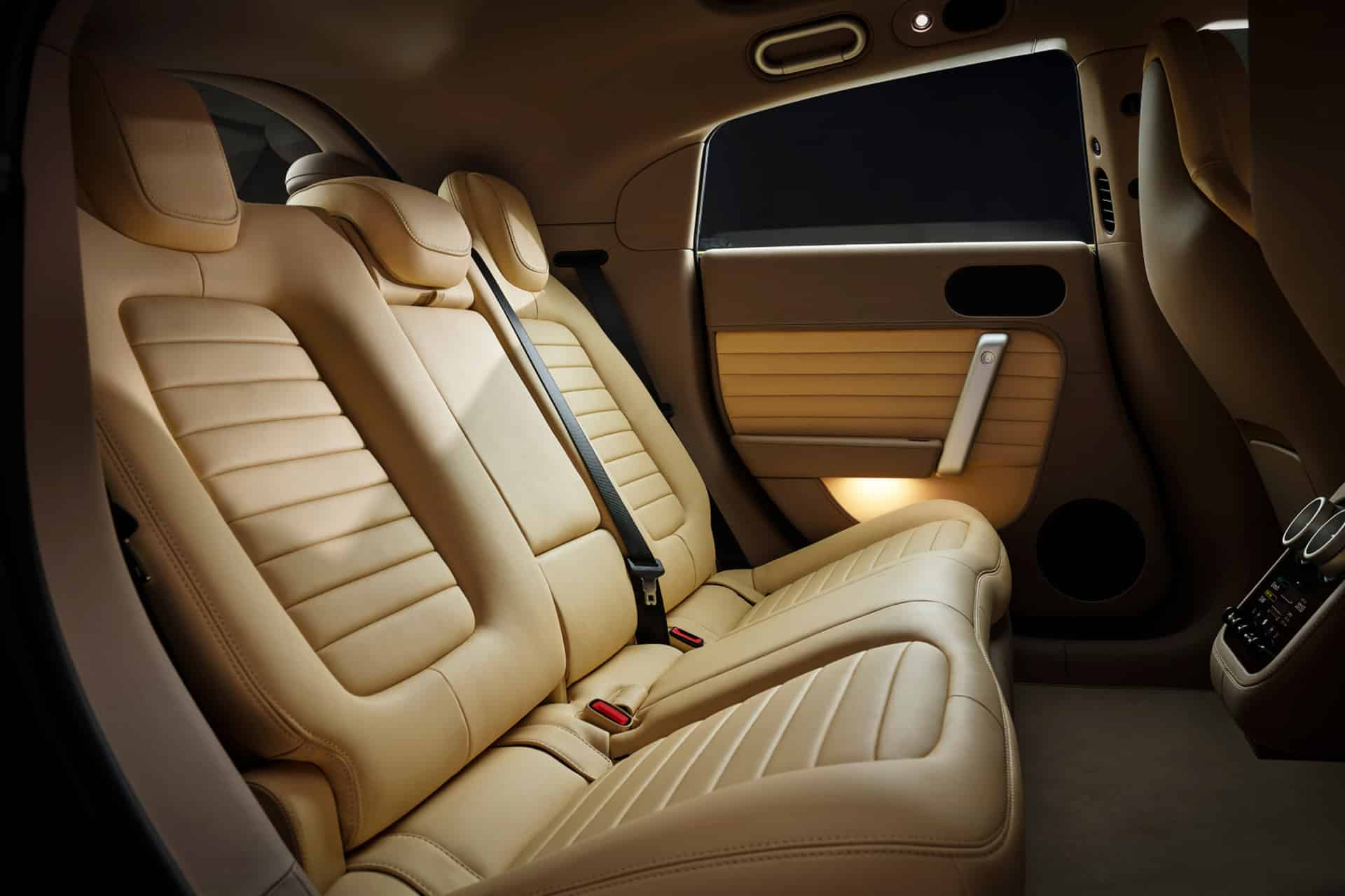 Beige leather rear seats of a modern luxury car with seat belts, detailed stitching, and interior side panels. The ambient lighting creates a warm, elegant atmosphere—enhanced by Ferrari Luce-inspired design details for a sophisticated touch.