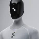 A humanoid robot with a sleek black faceplate and textured light gray body, featuring a geometric logo on its chest and minimalist, futuristic design—an embodiment of Apple robotics and physical AI innovation.