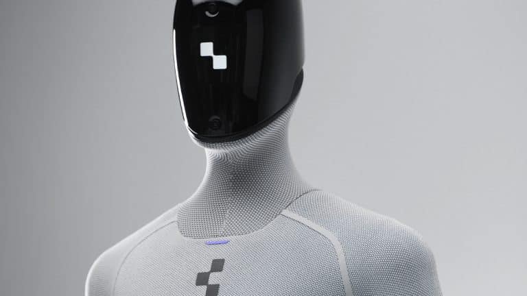 A humanoid robot with a sleek black faceplate and textured light gray body, featuring a geometric logo on its chest and minimalist, futuristic design—an embodiment of Apple robotics and physical AI innovation.