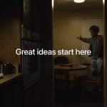 A person stands and gestures in a dimly lit kitchen-dining area, with the words "Great ideas start here" overlaid in white text—perfect inspiration for Mac Students seeking creativity at home.