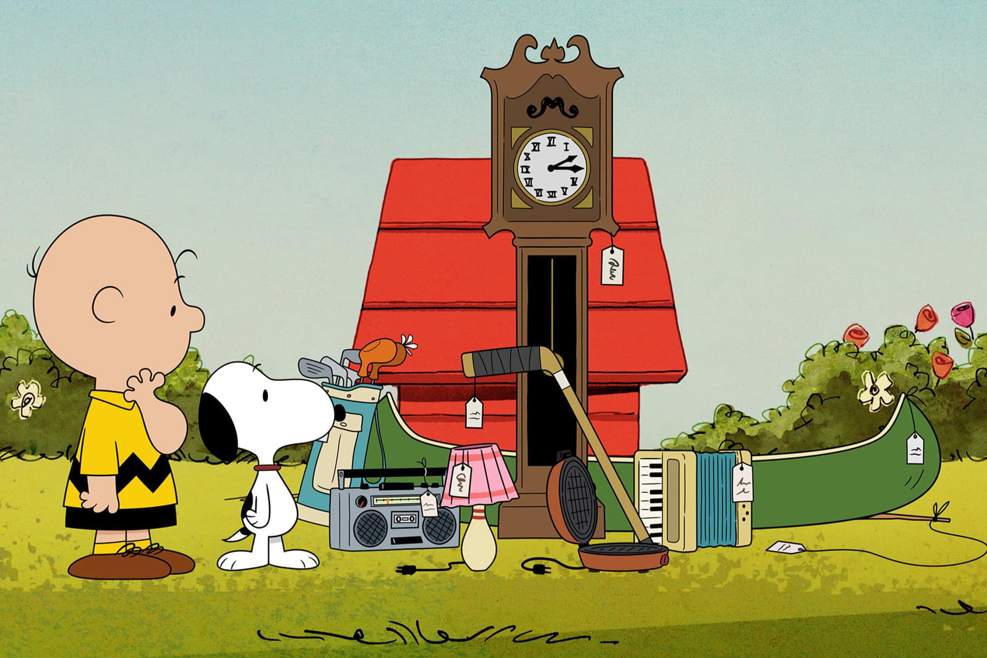 Charlie Brown and Snoopy, from Peanuts Apple TV, stand in front of Snoopy’s red doghouse, which features a large clock and tagged items like a record player and accordion outside, as if for a yard sale.