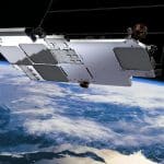 A satellite orbits above Earth, its metallic structure and solar panels gleaming in the foreground. Below, clouds and landmasses are visible, with the blue curve of the horizon—evoking an iPhone satellite view—against space in the background.