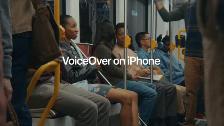 People sit and stand inside a subway car, some holding onto poles. "VoiceOver on iPhone" is displayed in large text at the center, highlighting the accessibility feature for visually impaired commuters.