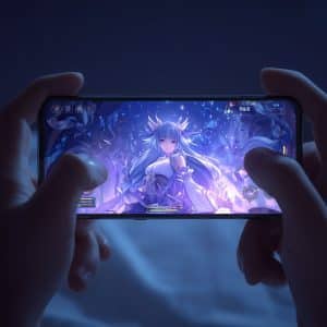 A person holds a smartphone in both hands, playing a fantasy video game featuring an anime-style character with long hair and glowing effects, reflecting how Apple's Ecosystem is reshaping the mobile entertainment industry. The dim lighting suggests nighttime gaming.
