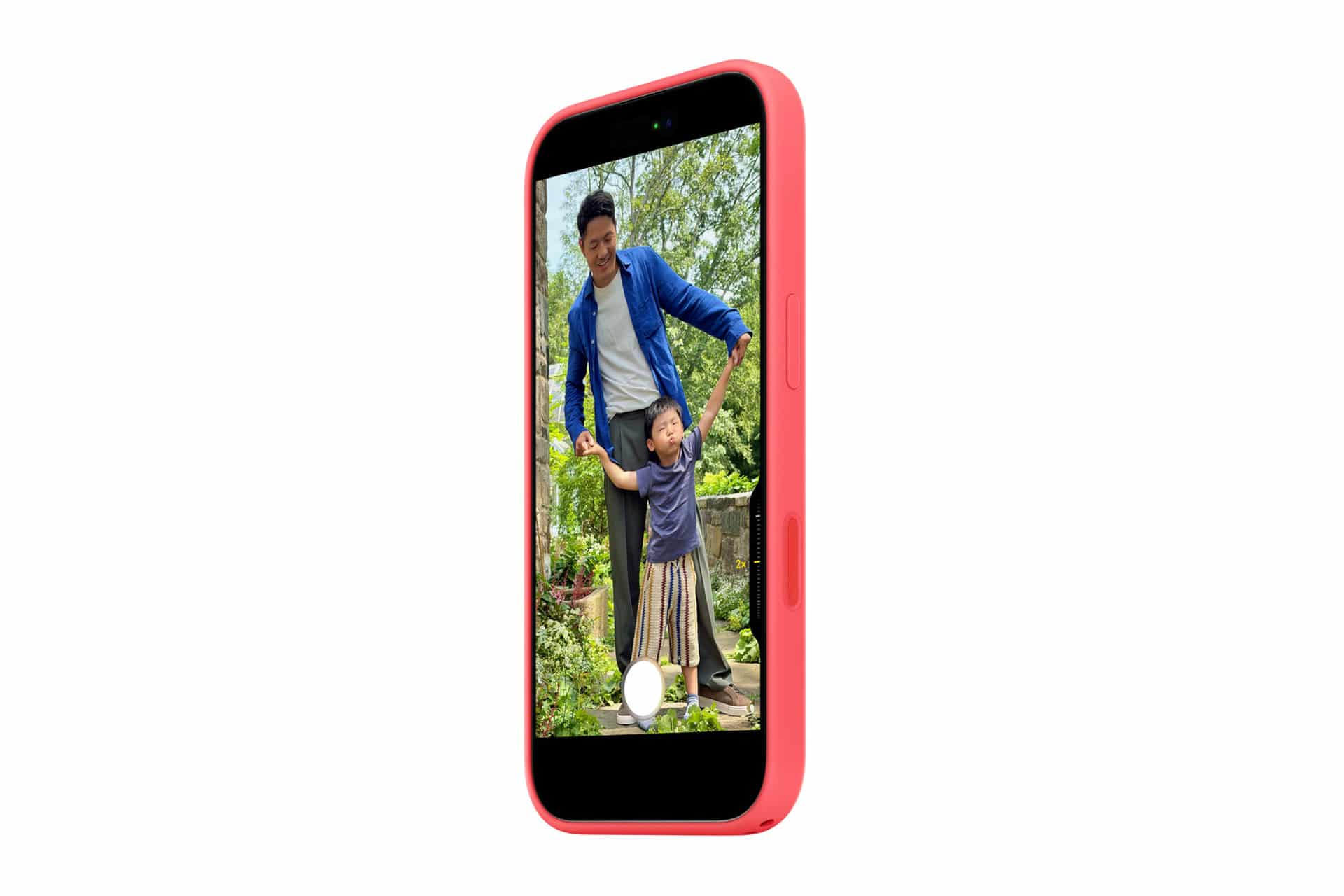 A pink smartphone with a MagSafe case displays a photo of an adult and child smiling together outdoors in a garden, surrounded by greenery, as the adult holds the child’s hands.