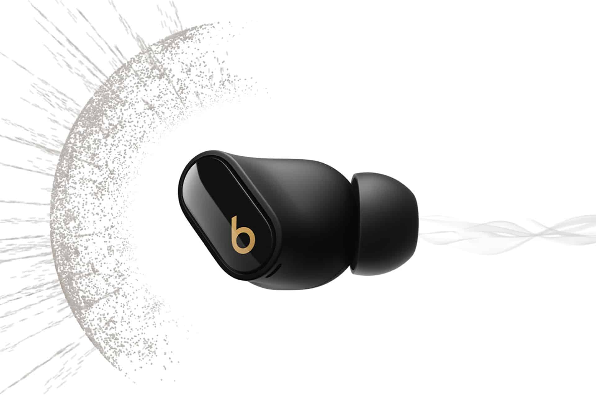A single black Beats Studio Buds wireless earbud with a gold "b" logo on the side is shown against a white background, featuring artistic gray and white swirls and splatter designs.