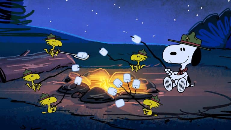 Snoopy and several yellow birds wearing scout hats roast marshmallows over a campfire at night in a forest, capturing a classic Peanuts moment sure to delight Charlie Brown fans and Apple TV viewers alike.