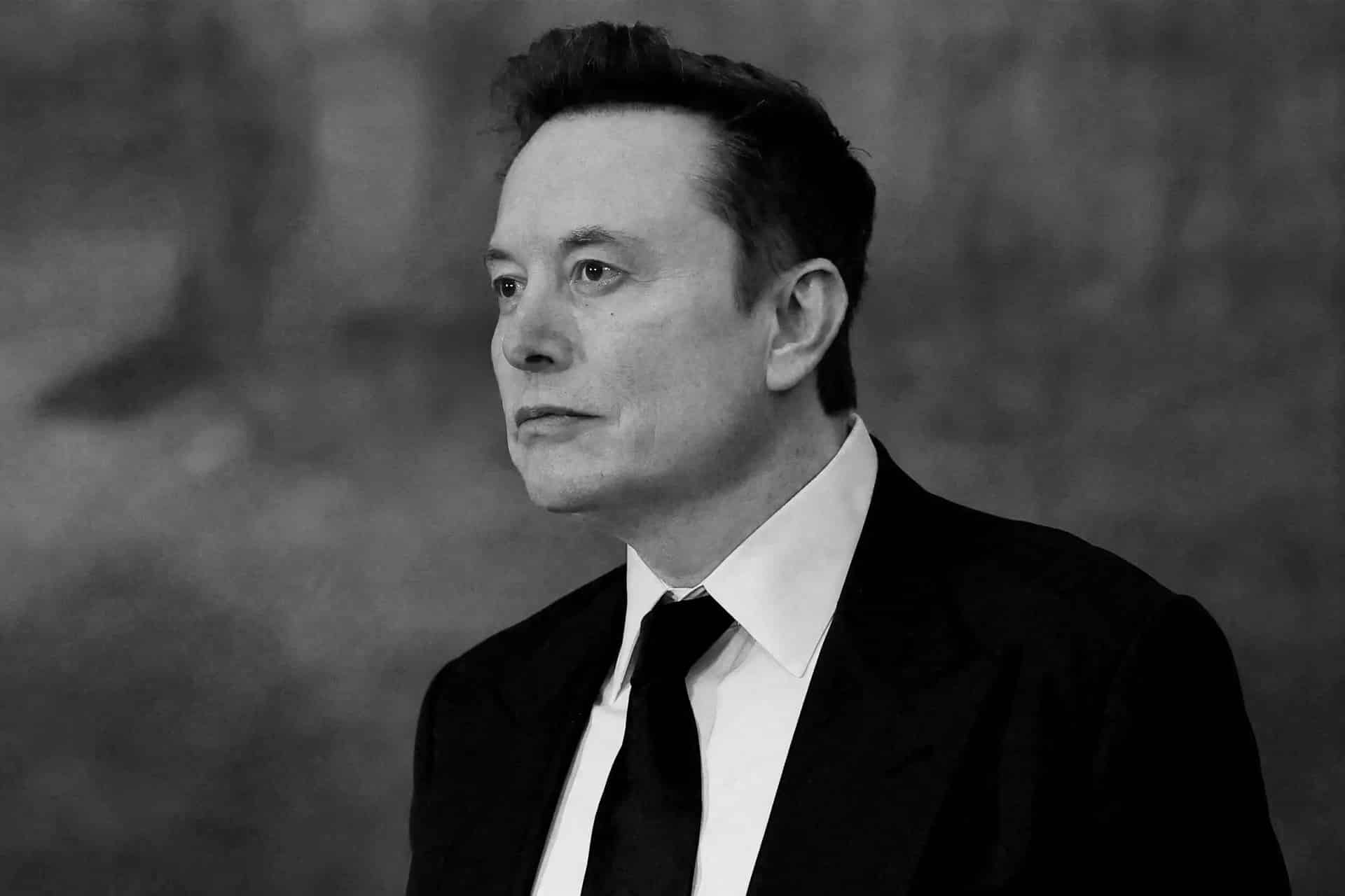 A man in a suit and tie looks thoughtfully to the side against a blurred background, the black and white image hinting at innovation—echoing the ambition of the SpaceX ecosystem.