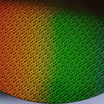 A close-up of a silicon wafer with a grid pattern reflecting a gradient of colors from orange to green to blue, highlighting the intricate design found in Apple chips and advanced M-series chips.