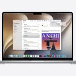 A MacBook running macOS 27 Golden Gate displays an email inbox with several messages listed and one selected, showing its contents on the right. The desktop features a light brown abstract background and a dock with various app icons at the bottom.