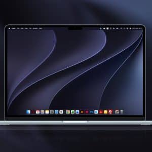 A silver laptop powered by Apple silicon displays a dark abstract wallpaper with curved lines. Running macOS 27 Golden Gate, its screen shows several application icons along the bottom dock, with a blurred background in dark shades.