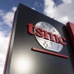 A sign featuring the TSMC logo, with red letters and a stylized silicon wafer graphic, stands against a partly cloudy sky—symbolizing the surge in TSMC AI chip demand.