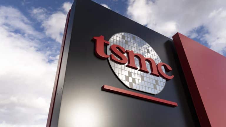 A sign featuring the TSMC logo, with red letters and a stylized silicon wafer graphic, stands against a partly cloudy sky—symbolizing the surge in TSMC AI chip demand.
