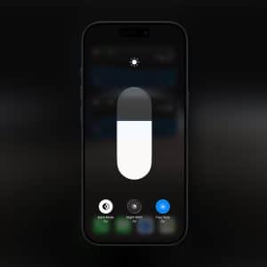 A smartphone screen shows the brightness control slider and options for Dark Mode, Night Shift, and True Tone settings, all turned off—similar to controls found on an Apple display. The Apple logo is visible in the bottom right corner.