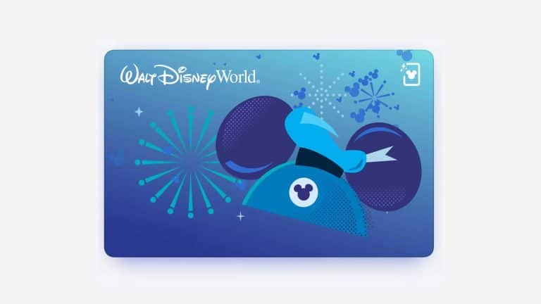 A blue Walt Disney World card featuring Mickey Mouse ears with a sorcerer’s hat, surrounded by fireworks and sparkles on a blue gradient background—perfect for adding to your Apple Wallet on iOS 27.