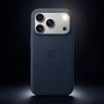 A dark blue Apple iPhone with three camera lenses and a textured case is shown upright against a dark background, spotlight illuminating the upper part. The Apple logo is visible, highlighting its LED flash alerts for iPhone calls.