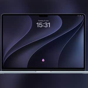 A silver Apple laptop with a dark abstract wallpaper on its screen, featuring the time 15:31 and date Tuesday, 9 June. The display showcases WWDC26 wallpapers on a blurred dark background, with an Apple logo in the bottom right corner.
