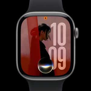 A smartwatch with a black band displays the time as 10:09. Its screen shows a large profile photo, bold numbers, and a circular graphic at the bottom center, possibly representing a voice assistant—showcasing watchOS 27 compatibility.