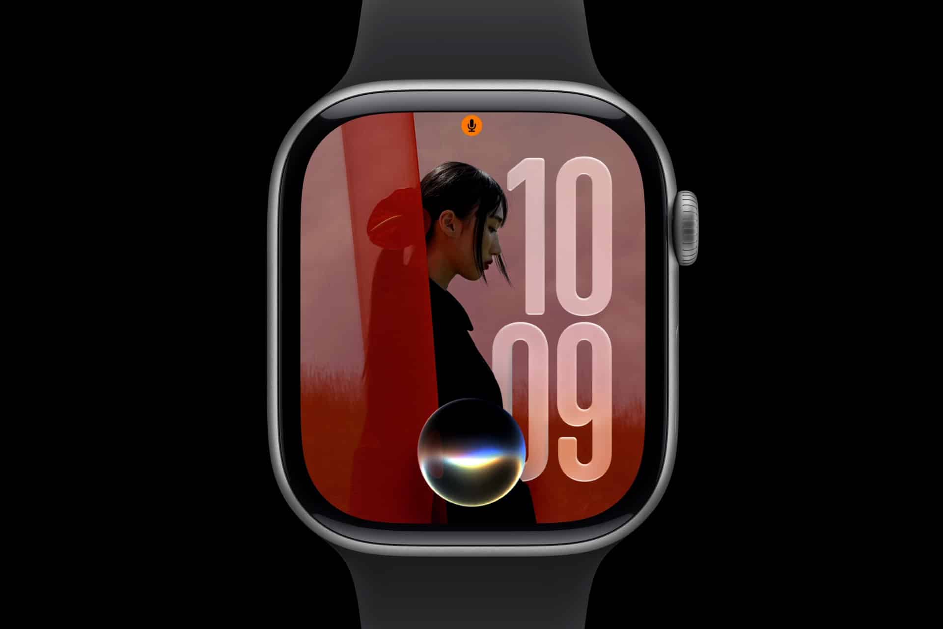 A smartwatch with a black band displays the time as 10:09. Its screen shows a large profile photo, bold numbers, and a circular graphic at the bottom center, possibly representing a voice assistant—showcasing watchOS 27 compatibility.