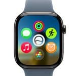 A close-up of a smartwatch screen displaying colorful app icons, including activity rings and music, with a blurred scenic background. The watch features a blue strap and highlights watchOS 27 compatibility.