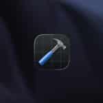 A digital icon of a hammer with a blue handle over a black grid background is centered on a dark, blurred surface. The Apple logo and "Apple" with "WWDC26" appear in the lower right corner, hinting at exciting news for Apple developers.