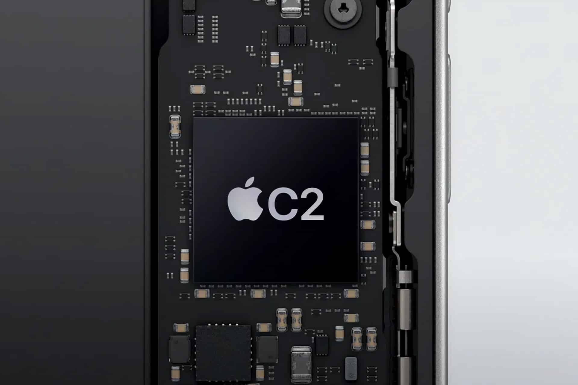Close-up of an electronic circuit board inside a device, featuring a black chip labeled with the Apple logo and "C2" at the center. Surrounding components and connectors are visible in detail, suggesting advanced technology possibly linked to next-generation iPhone 18 hardware or 5G satellite direct-to-satellite connectivity.