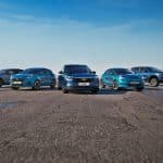 Five blue Ford vehicles, including an electric pickup, are parked in a semi-circle on an empty road under a clear blue sky, with open landscape in the background—showcasing the future of driving with features like Ford Apple Maps integration.