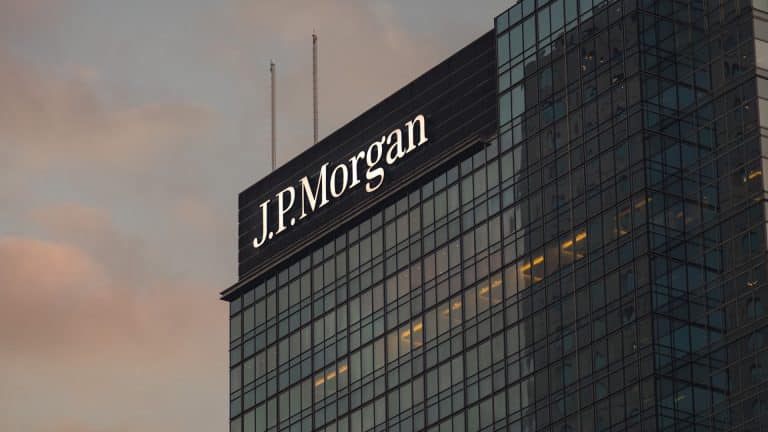 A glass skyscraper with the illuminated "J.P. Morgan" logo near the top, photographed at sunset with a cloudy sky in the background, highlights the firm’s influence on markets like Apple stock and its recent AAPL target announcements.