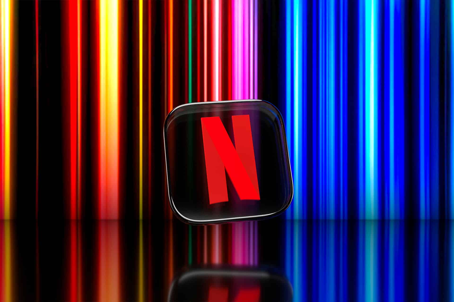 A black square with a red "N" Netflix logo is centered in front of a background of vertical neon light streaks in various colors, evoking the vibrant energy of a streaming lineup.