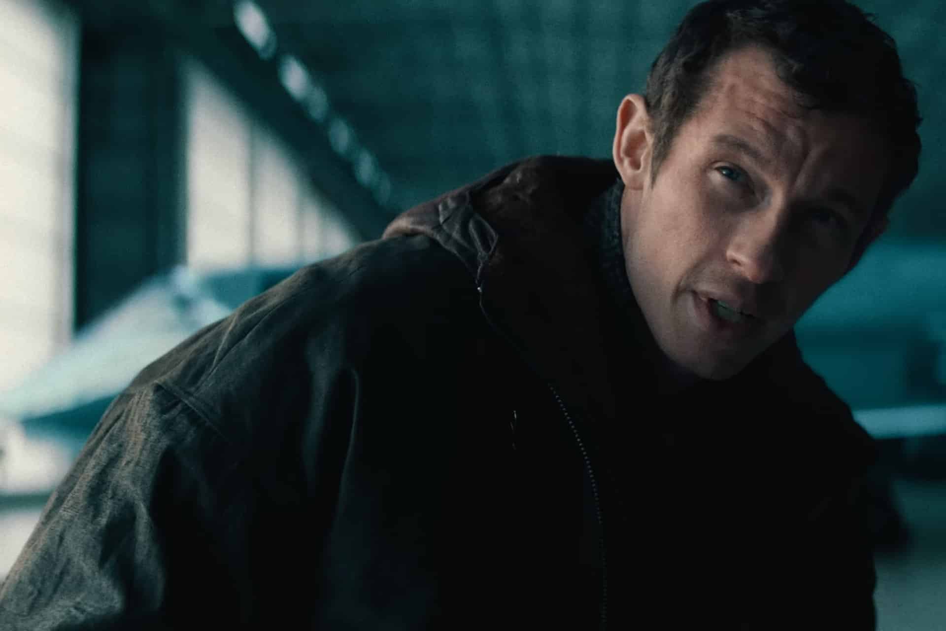 A man in a dark jacket leans forward indoors, with a serious expression, in a building with large windows and a high ceiling in the background—evoking the intense, high-tech atmosphere seen in the Neuromancer teaser for the upcoming Apple TV sci-fi series.