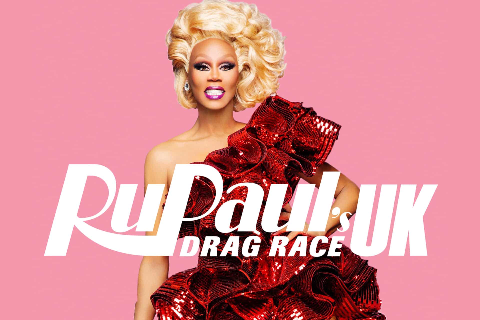 A drag queen with voluminous blonde hair and bold makeup poses in a shiny red ruffled dress against a pink background. Large white text reads “RuPaul’s Drag Race UK,” available through your TV show purchases in the Apple TV app.