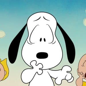 Snoopy looks surprised with one paw up, while Sally and Charlie Brown stand on either side, both appearing shocked. Set against a blue sky with simple clouds, this scene perfectly captures the whimsical charm of a classic Peanuts special as seen in Snoopy Presents on Apple TV.