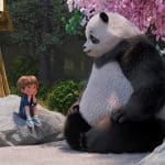 A young child sits on a rock, facing a large panda under pink cherry blossoms. Both appear relaxed, surrounded by trees and a bamboo structure in the background—a tranquil moment inspired by the animated series Stillwater, capturing the gentle wisdom and calm of Stillwater season 5.