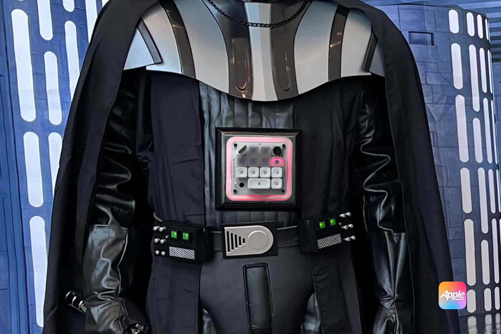 A person in a Darth Vader costume stands with a mechanical keyboard on their chest. The Apple logo is in the bottom right corner, and the background resembles a spaceship interior—an aesthetic that wouldn’t feel out of place in a Jony Ive design.