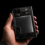 A hand holds a foldable iPhone with a transparent back, revealing its internal components and the Foldable iPhone battery, against a black background. The Apple logo is visible in the lower right corner.